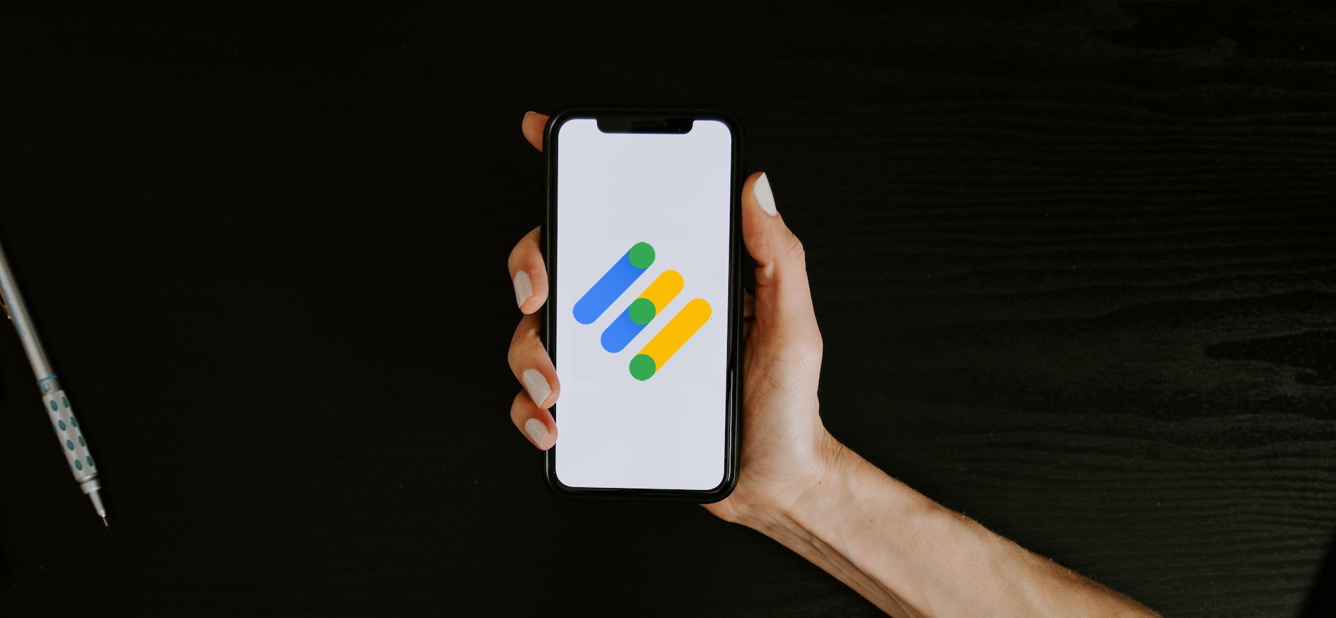 A woman's hand holds a smartphone displaying the Google Drive logo against a black background.