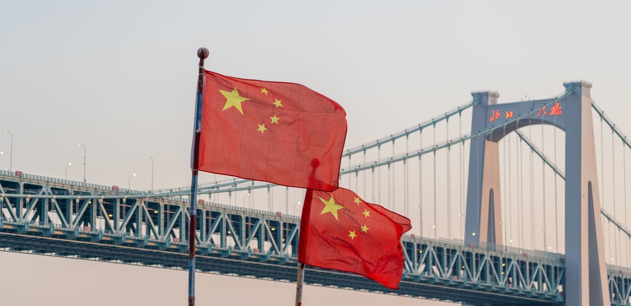 Chinese flags and a bridge at sunset.