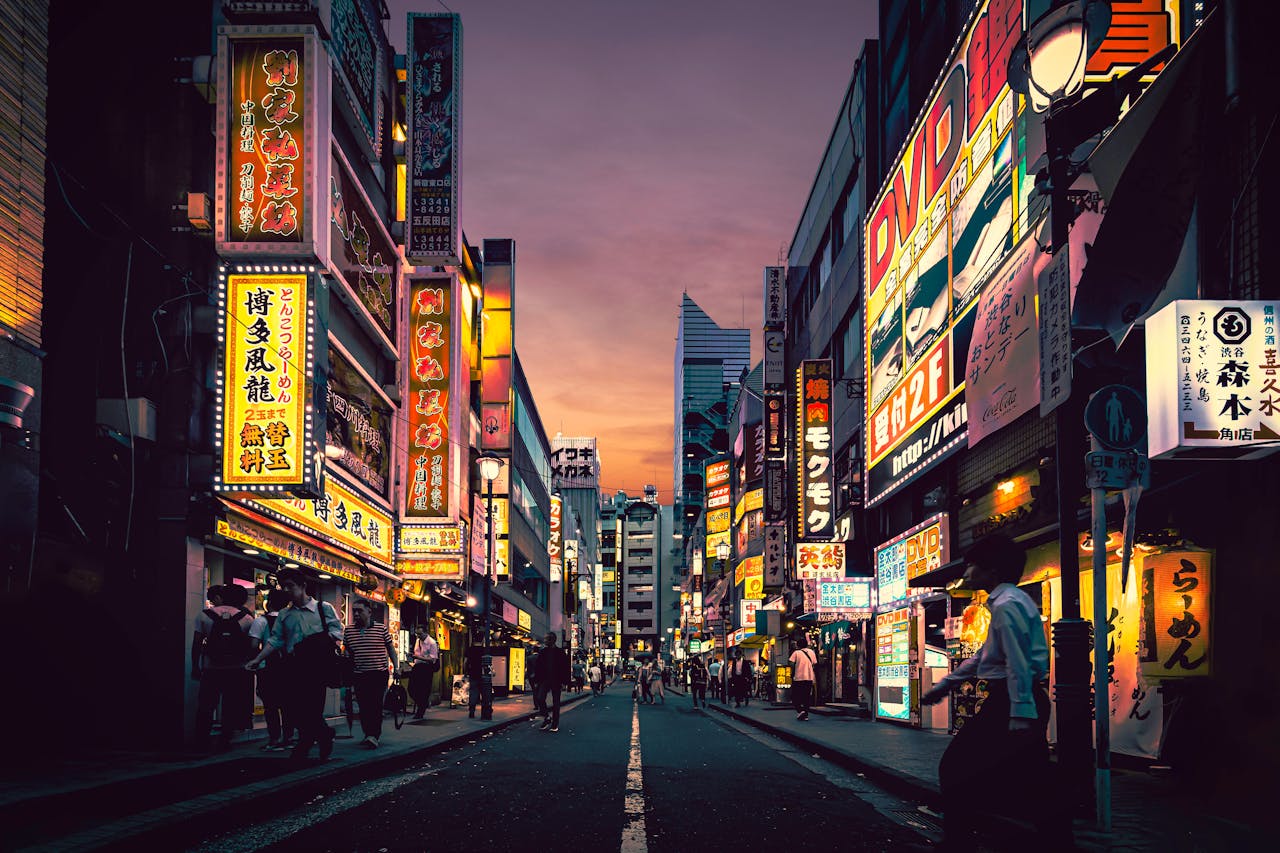 A Japanese city at sunset with people walking on its streets and bright neons.