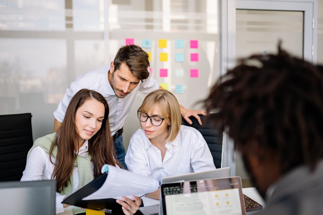 Three people sitting in an office space, looking at a report.